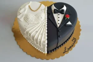 کیک عروسی : کیک به شکل قلب به دونیمه ،یک نیمه با نمای کت داماد و نیمه دیگر با نمای لباس عروس