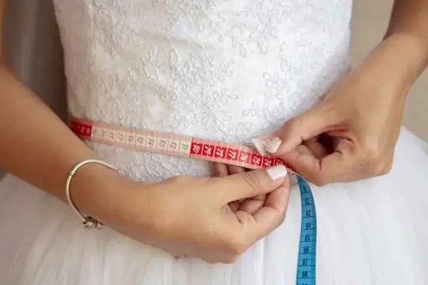 تناسب اندام عروس : عروسی که بامتر دور کمرش را اندازه میگیرد