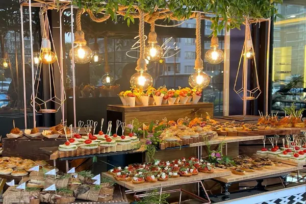 میوه وشیرینی عروسی : چند سینی مملو از شرینی و میوه با لامپهایی آیزان از سقف و تم چوبی