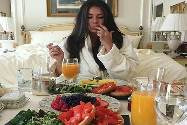 سینی غذا و میوه و خانومی با لیاس خواب زمستانی در حال خوردن